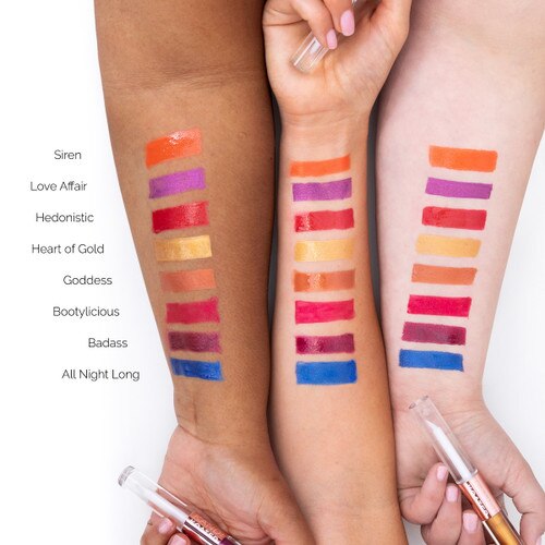 An image of three outstretched arms of differing skin tones showcasing different colors of Slay metallic lip glosses in swatches on each arm for comparison. Each hand clasps a different tube.